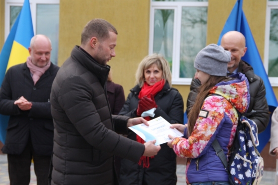 Павел Кириленко вручает сертификат на квартиру переселенке